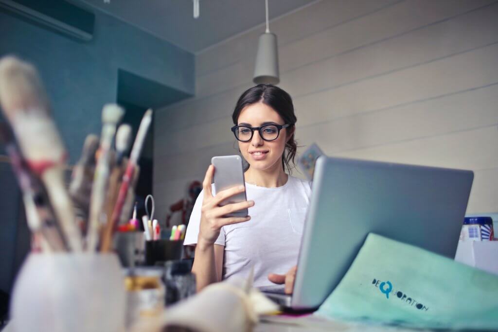 Woman sitting at desk looking at phone | Small Business Attorney Services