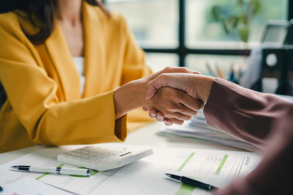 Businesswomen shaking hands after reaching an agreement on a deal during a meeting at the office